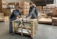 Zwei Mitarbeiter packen eine Kiste mit Steinen