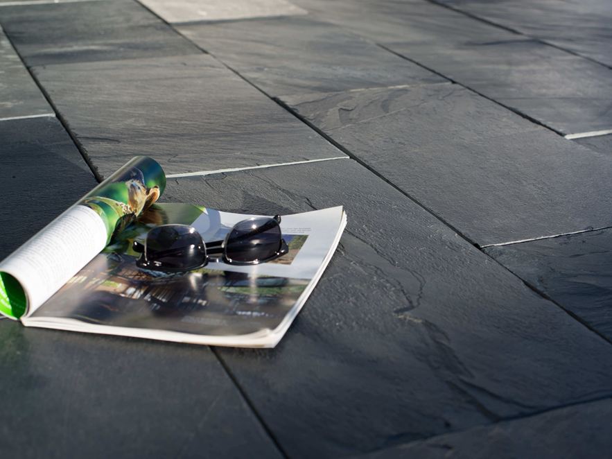 Anthrazitton und markante Schieferungen Eine Zeitschrift und eine Sonnenbrille auf Schieferplatten in der Sonne